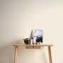 Cremeweiße, strukturierte Vliestapete Uni Matt FSC® an Wand hinter Holztisch.