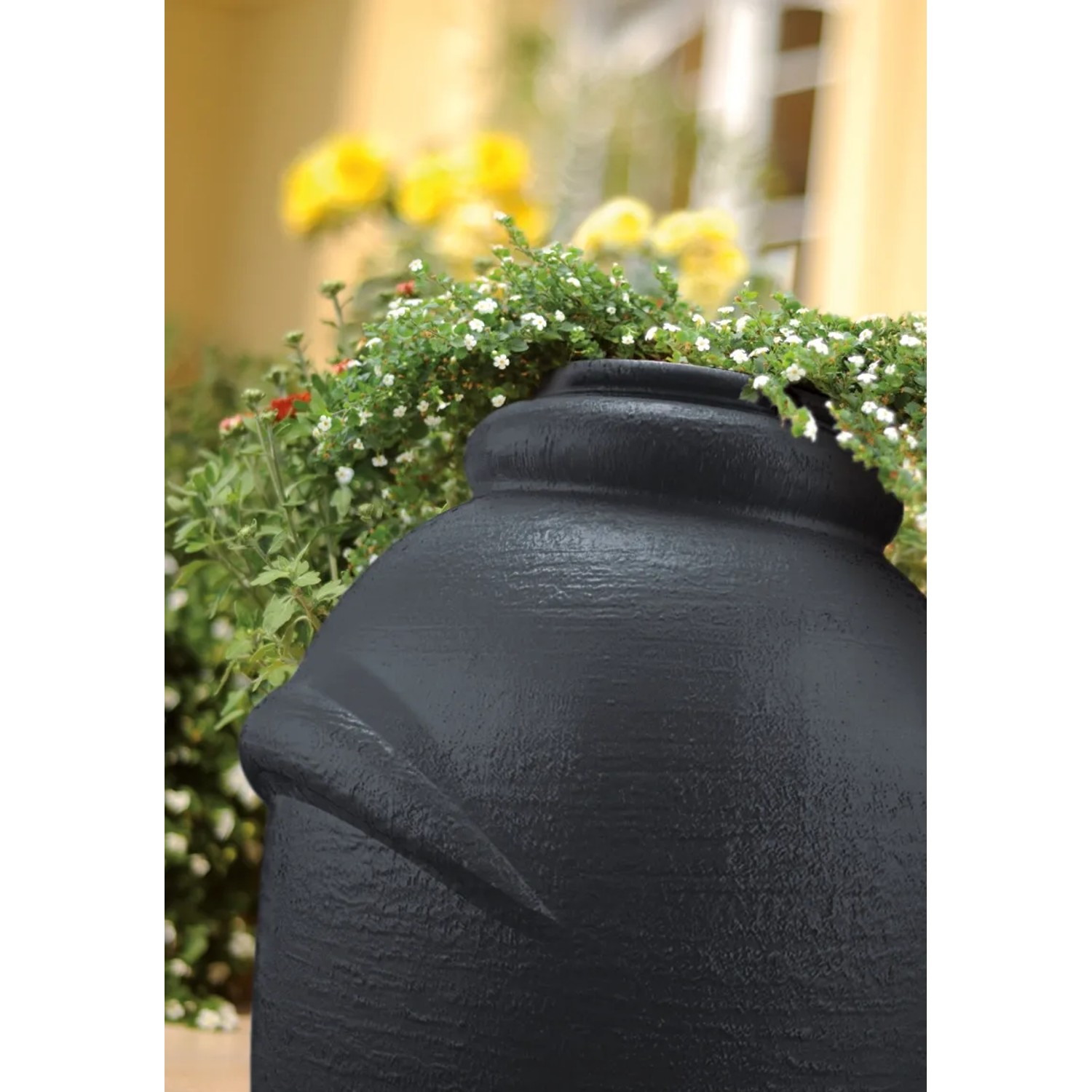 Anthrazitfarbene Waterform Regentonne Aquacan 360 l im Amphoren-Design vor Pflanzen.