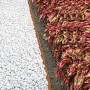 Bellissa Rasenkante Cortenstahl, Edelrost-Optik, trennt weißen Kies von Beet mit bunten Blättern.