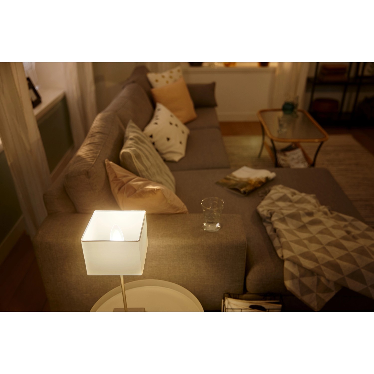Philips Hue E14 Doppelpack: Zwei warmweiße Leuchtmittel in Lampe auf Tisch im Wohnzimmer.