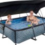 Grauer EXIT Stone Pool 220x150 mit Sonnensegel und Filterpumpe, genutzt von Erwachsenem und zwei Kindern.