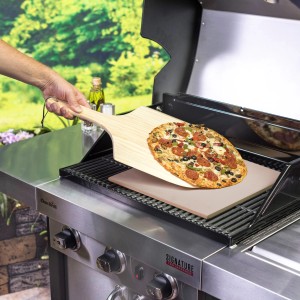 Char-Broil Pizzastein Set mit Holzschieber auf Grill, Pizza wird serviert.