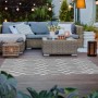Grauer Primaflor In- und Outdoorteppich Reverso Geo River (160x220cm) auf einer Terrasse.