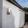 Moderne Lutec LED-Außenwandleuchte Leda mit Bewegungsmelder an weißer Hauswand.
