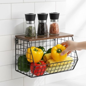 Schwarzer Metall-Obstkorb Wandregal mit Holzablage an weißer Wand, gefüllt mit Paprika & Mais. Küchenorganizer.