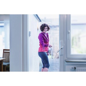 Frau öffnet Terrassentür mit Abus HomeTec Pro Funk-Fensterantrieb in Silber.