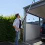 Mann reinigt Dachrinne mit Gardena combisystem-Dachrinnenreiniger und Teleskopstiel.