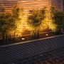 Paulmann Outdoor-Bodeneinbaustrahler Floor Edelstahl, rund, beleuchtet Pflanzen in einem Beet.