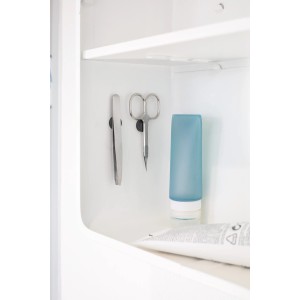 Fix-o-moll Magnetscheiben im Einsatz: Pinzette und Schere haften an einer weißen Schrankwand.