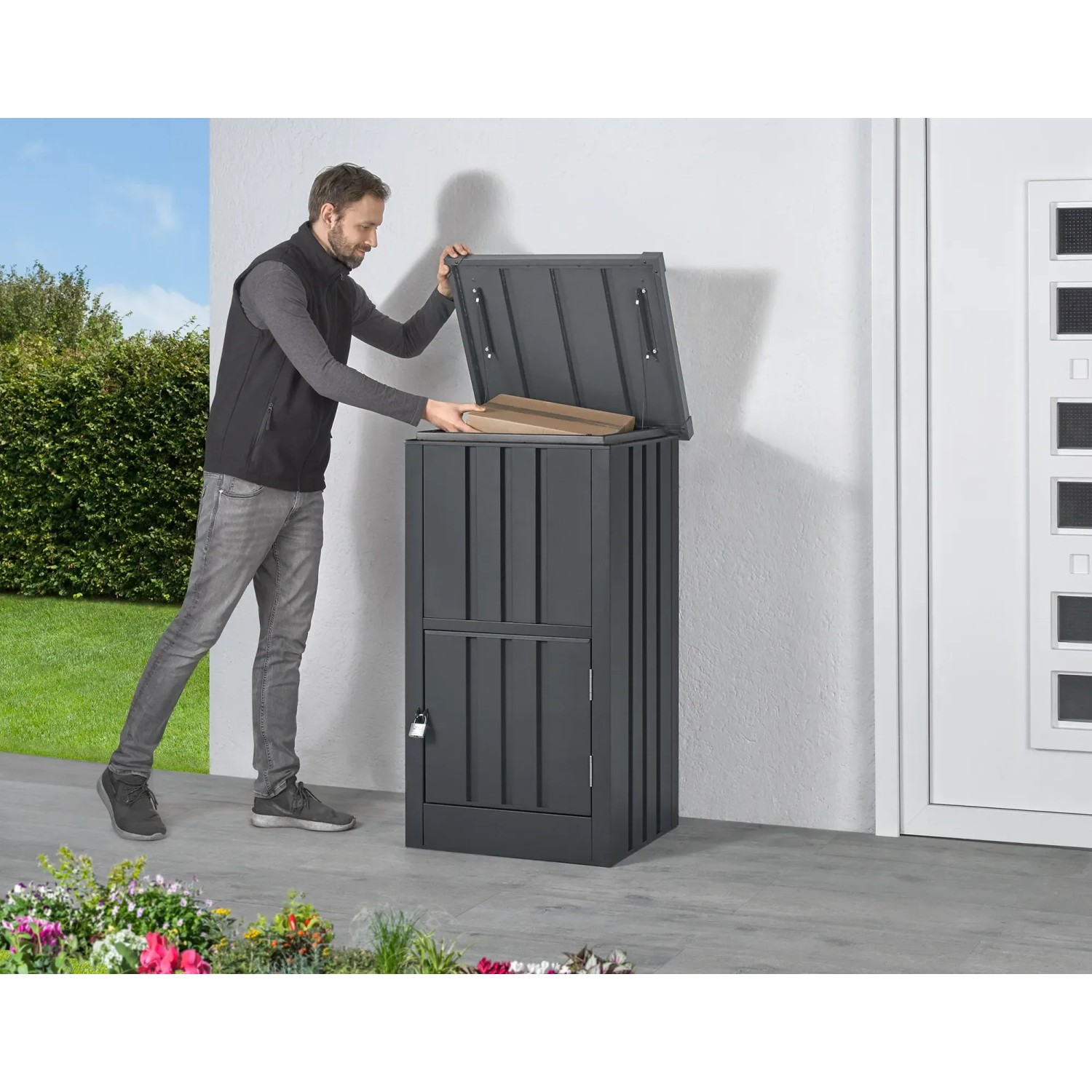Floraworld Paketbox aus Stahl, abschließbar, anthrazit, mit Mann beim Einlegen eines Pakets.