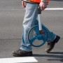 Person mit Bosch Professional Messrad GWM 32 zur Entfernungsmessung auf Asphalt.