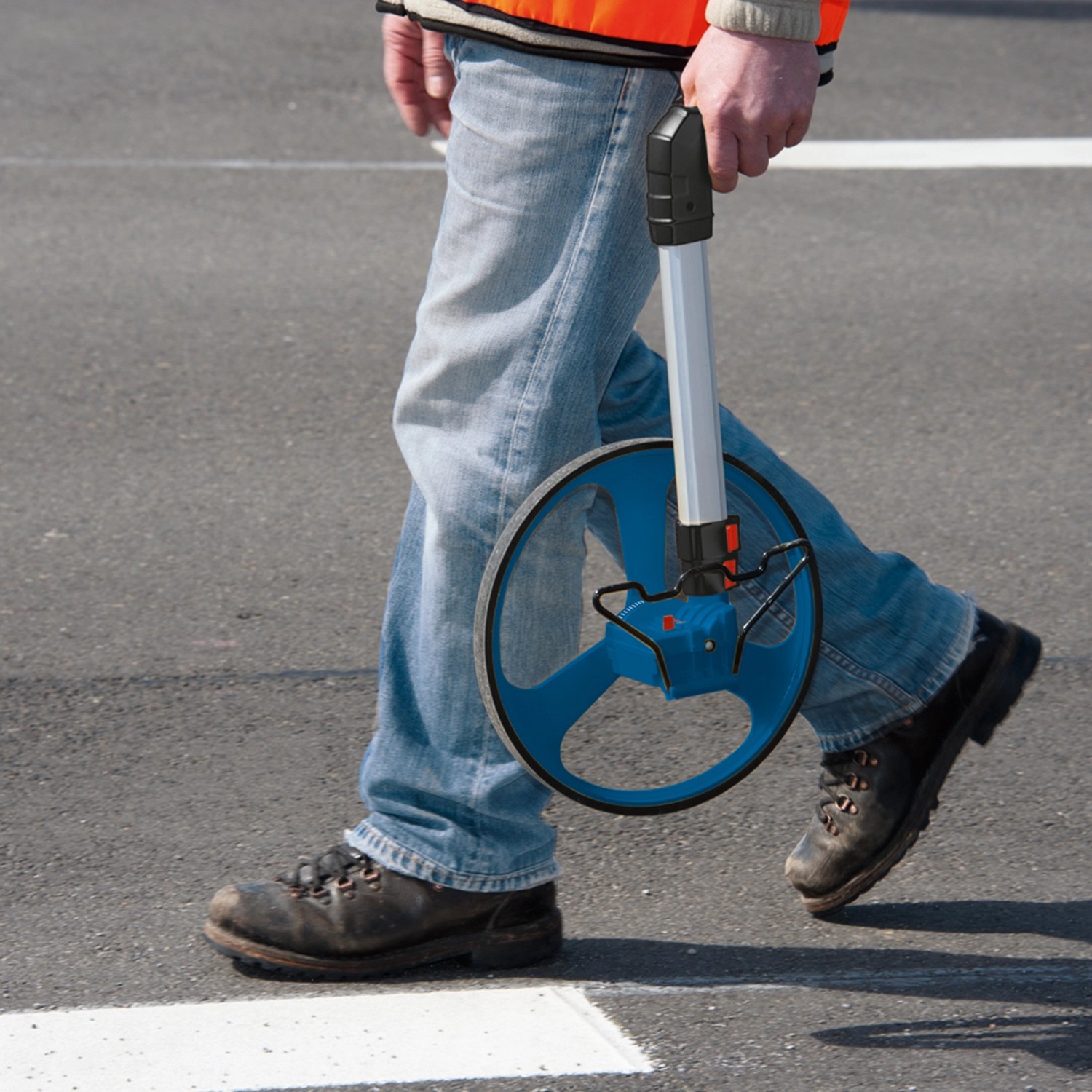 Person mit Bosch Professional Messrad GWM 32 zur Entfernungsmessung auf Asphalt.