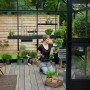 Juliana Gewächshaus Oase 13 Anthrazit mit Frau und Pflanzen im Garten.