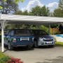 Weißer Skan Holz Doppelcarport Spessart mit zwei geparkten Autos.
