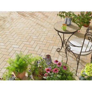 Verlegtes Rechteck-Pflaster Beton Sandstein (20x10x6 cm) auf einer Terrasse mit Gartenmöbeln und Pflanzen.