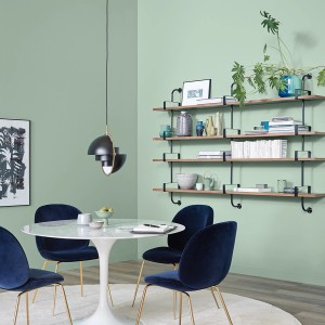Esszimmer mit Schöner Wohnen Wandfarbe Spa Grün, matt. Regale und blaue Stühle.