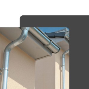 Silberne, verzinkte Zambelli Fallrohrschelle DN 100 befestigt ein Ablaufrohr an einer hellen Hausfassade.