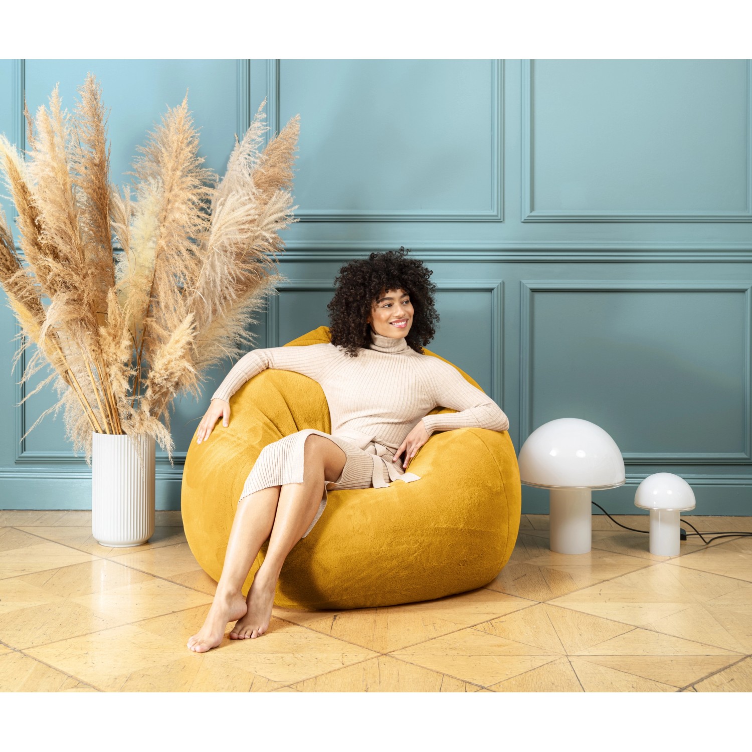 Frau sitzt entspannt im gelben Sitting Point Sitzsack BeanBag Softy 220 l.