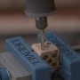 Dremel 9903DM Wolframkarbid-Fräser im Einsatz an einem Holzwürfel in einem Schraubstock.