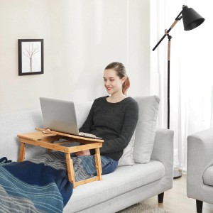 Frau nutzt Songmics Laptoptisch aus Bambus (natur) auf einem Sofa für entspanntes Arbeiten.