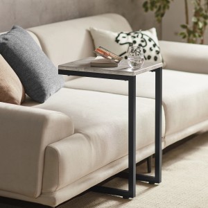 Grauer SoBuy Betttisch/Beistelltisch FBT44-HG neben Sofa mit Buch und Glas Wasser.