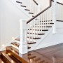 Glänzende Holztreppe mit dunklen Stufen und weißem Geländer. Der Parkettlack und Treppenlack schützt Holzflächen.