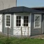 Unbehandeltes Alpholz Gartenhaus Rhein mit Walmdach, grau gestrichen, mit weißen Fenstern und Türen.