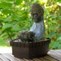 Zimmerbrunnen Buddha mit Lotusblüte in Steinoptik und Deko-Steinen für entspannende Atmosphäre.
