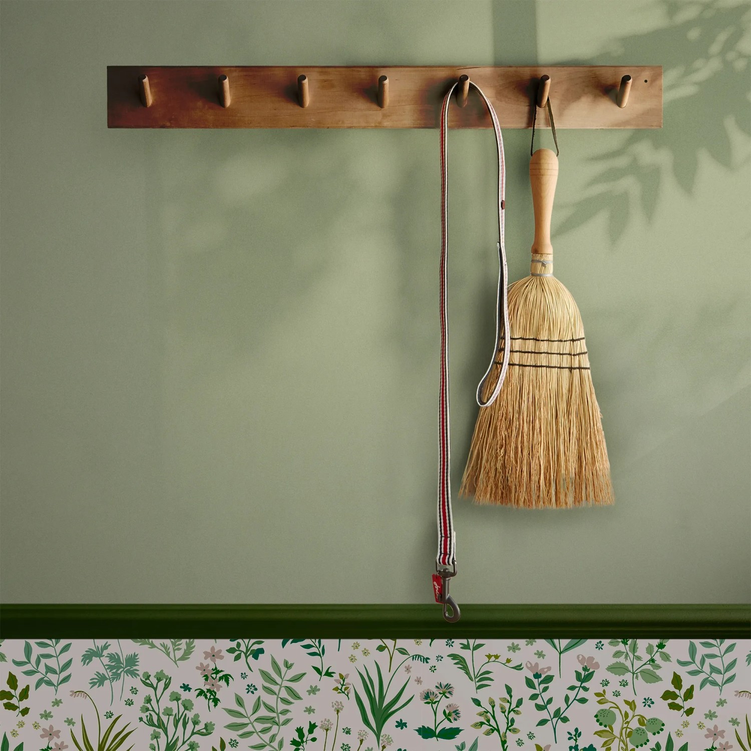 Helle, grüne Joules Vliestapete Uni (10m x 52cm) an Wand mit Besen und Leine.