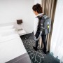 Frau saugt Teppich mit Kärcher Akku-Rucksacksauger BVL 5/1 Bp. Akkugerät für komfortable Reinigung.