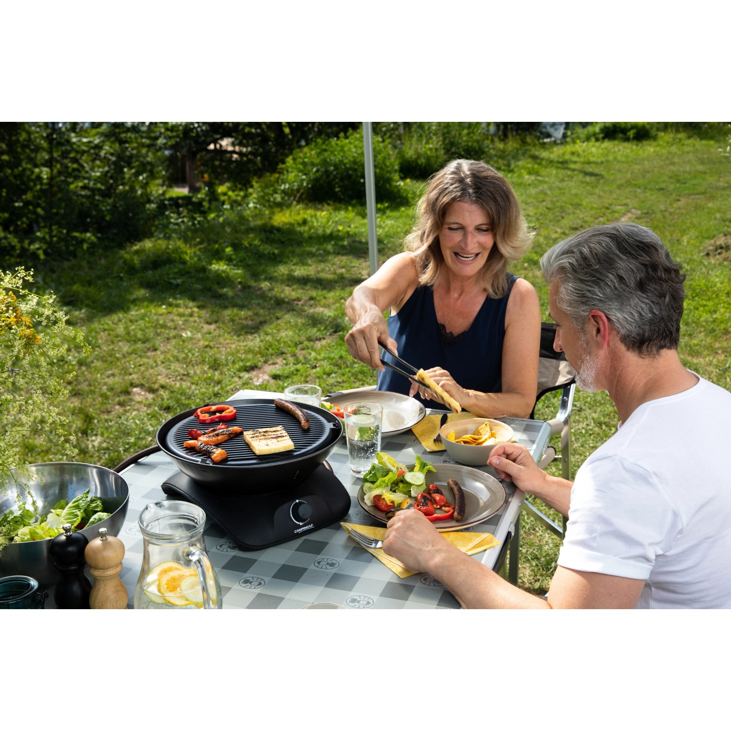 Campingaz 360° Tisch-Grill beim Grillen von Gemüse und Halloumi im Garten.