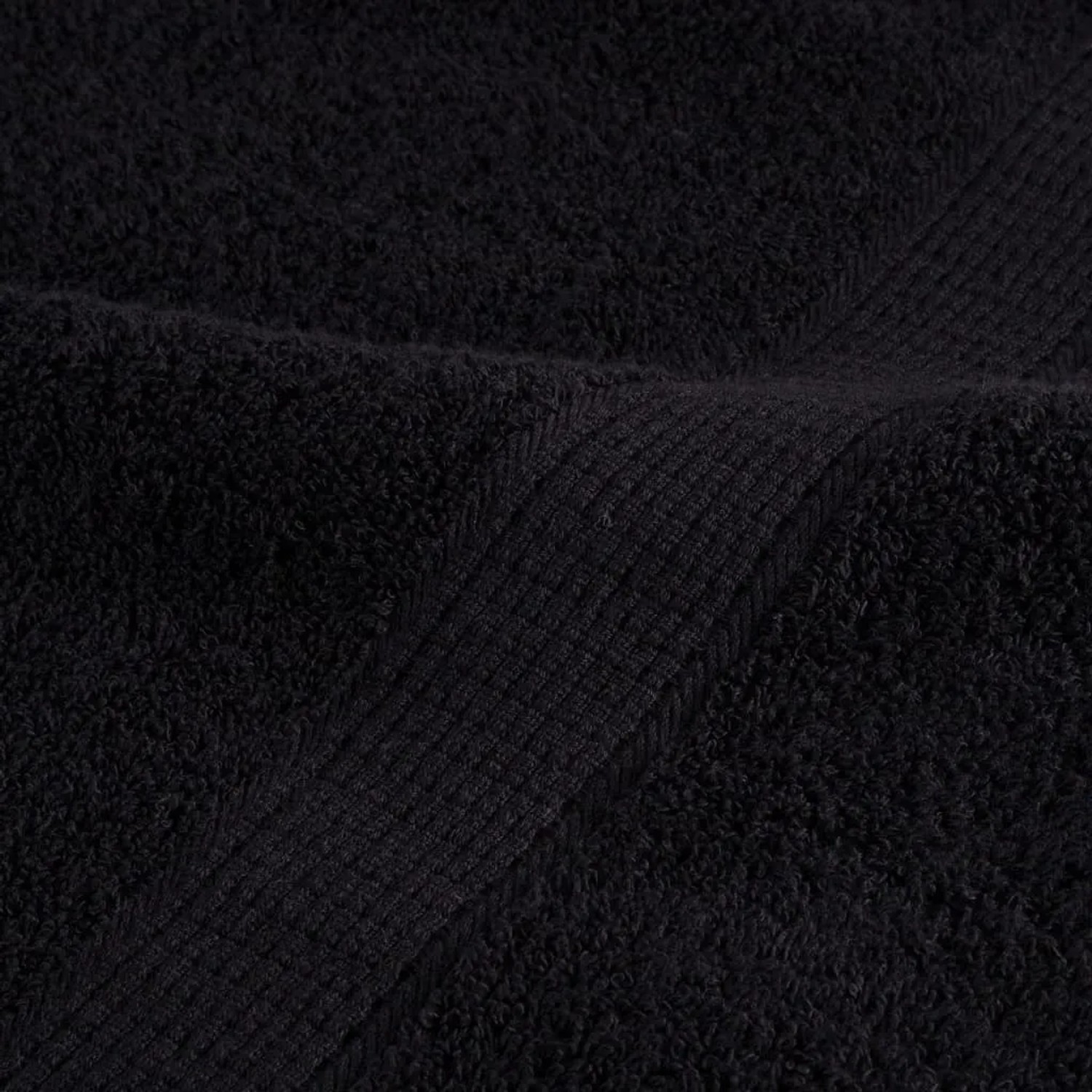 Detailaufnahme: Schwarzes, flauschiges Handtuch aus 100% Baumwolle, Teil eines 8-teiligen Sets.