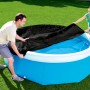 Bestway Flowclear Poolabdeckung, schwarz, Ø 244 cm, wird von zwei Personen über einen Pool gezogen.