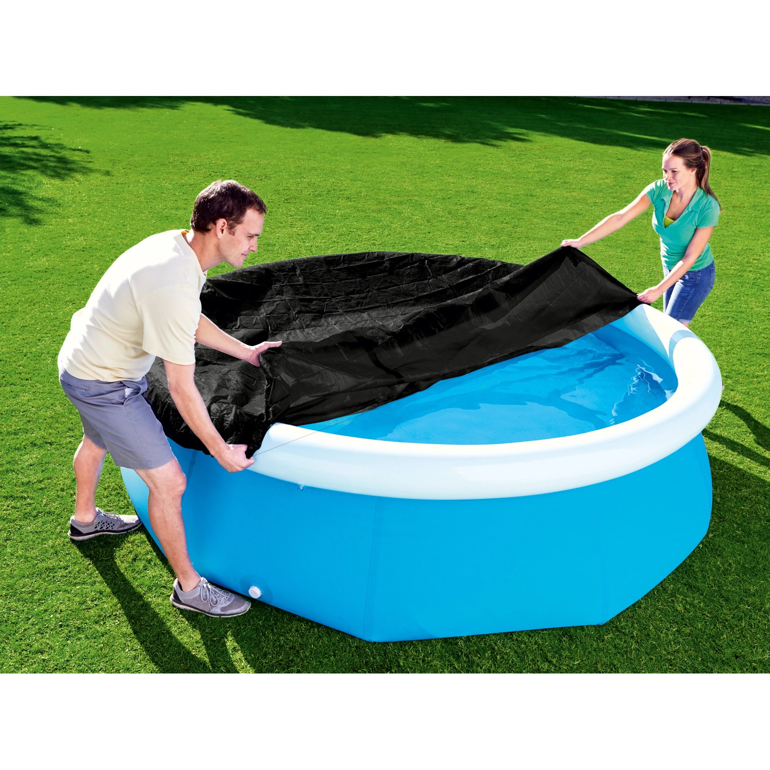 Bestway Flowclear Poolabdeckung, schwarz, Ø 244 cm, wird von zwei Personen über einen Pool gezogen.