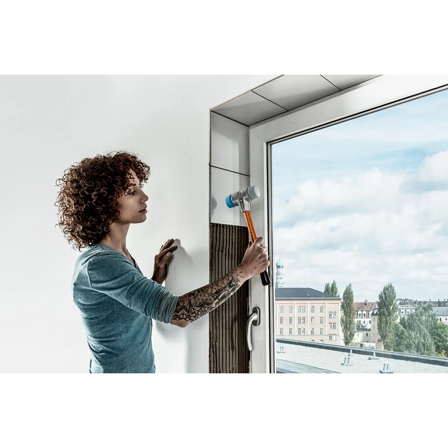 Frau verlegt Fliesen mit Halder Schonhammer (TPE-soft, TPE-mid, Alu-Gehäuse, Holzstiel, 50mm).