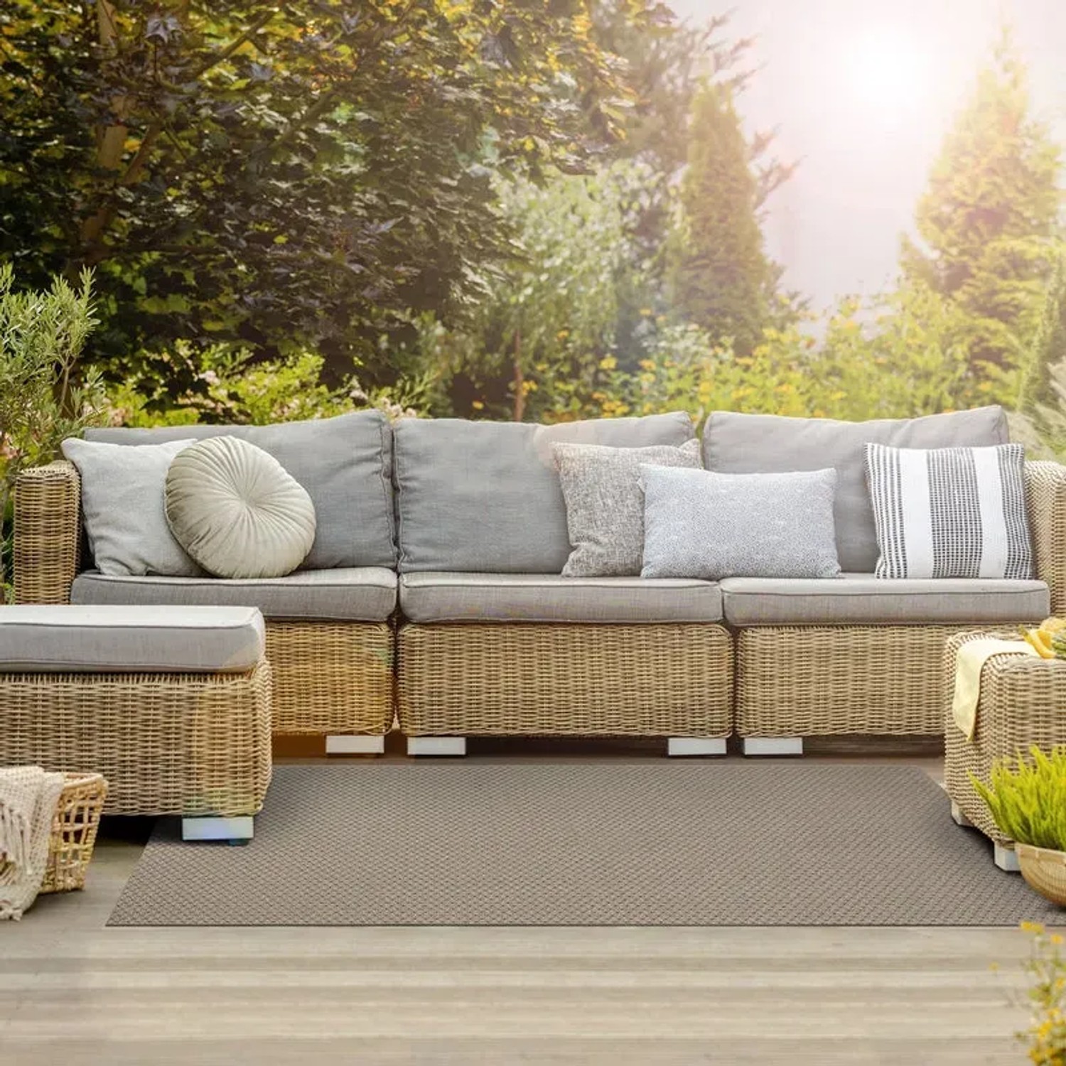 Wetterfester, grauer KARAT Outdoor Teppich Pavia (90x150 cm) auf einer Terrasse mit Gartenmöbeln.