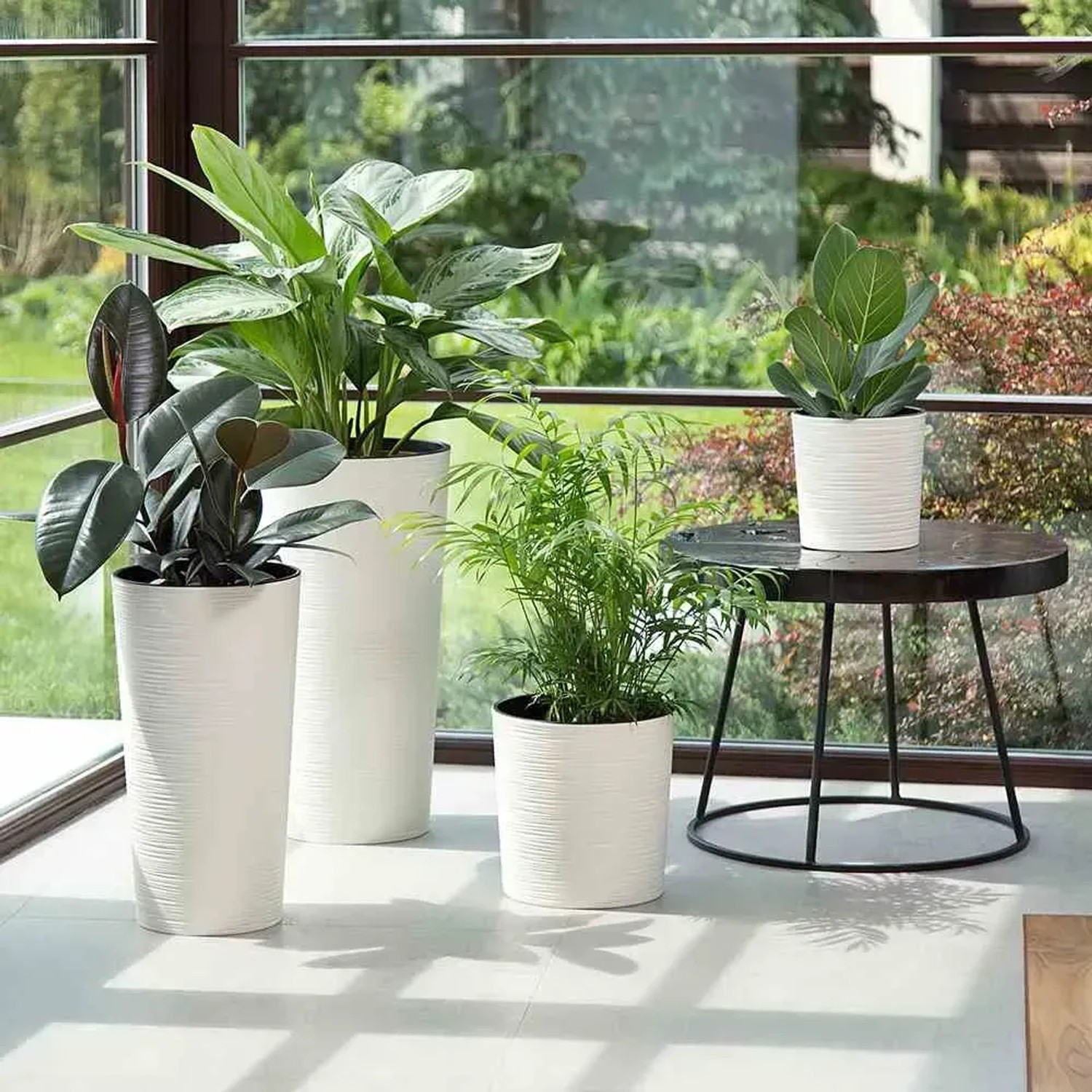 Weiße Siena Garden Blumentöpfe 'Modern Lens' mit Rillenstruktur und verschiedenen Pflanzen.