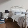 Schlafzimmer mit weißer Vliestapete Elegance 2 Uni Weiß FSC® an der Wand.
