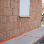 Orangefarbenes Scotch Klebeband High Visibility am Sockel eines Hauses.