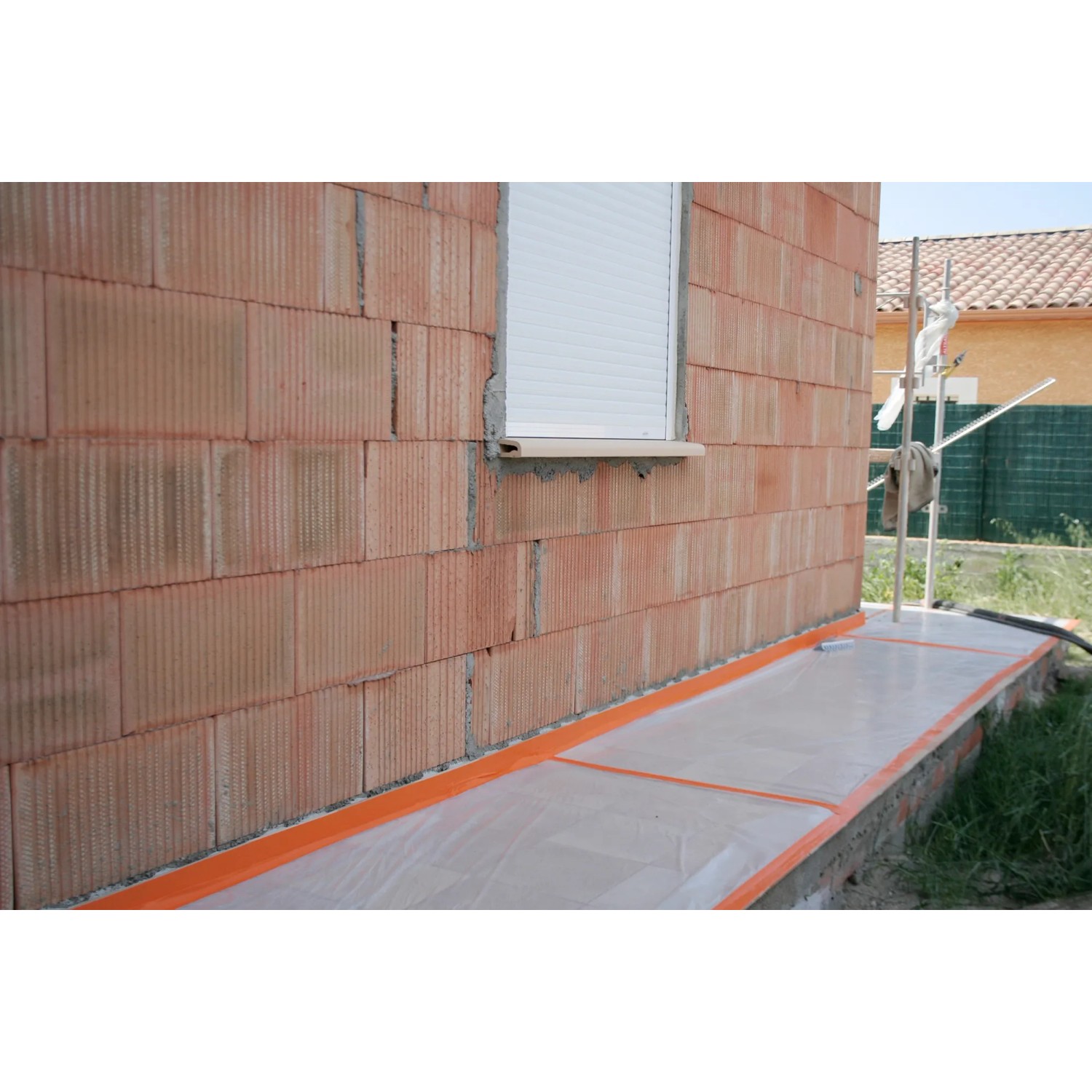 Orangefarbenes Scotch Klebeband High Visibility am Sockel eines Hauses.
