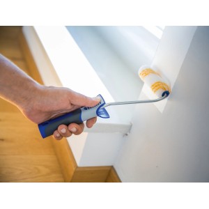 Hand streicht Wand mit LUX Dispersionswalze 12 cm. Farbwalze mit blau-grauem Griff.