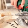 Bosch PST 700 E Stichsäge in Aktion beim Holzsägen, mit Sägeblättern auf Werkbank.