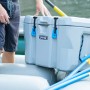 Dunkelgraue Kühlbox aus Kunststoff mit Tragegriffen auf einem Schlauchboot. Ideal für Camping und Outdoor.