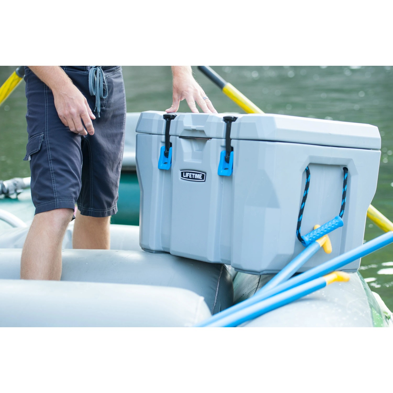 Dunkelgraue Kühlbox aus Kunststoff mit Tragegriffen auf einem Schlauchboot. Ideal für Camping und Outdoor.