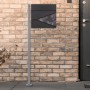 ML-Design Standbriefkasten mit Zeitungsfach und Pfosten, Edelstahl Silber vor einer Backsteinwand.