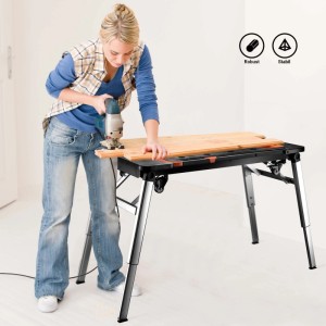 Frau sägt Holz auf schwarzer Wiltec 7in1 Werkbank mit silbernen Beinen; multifunktionaler Werktisch, robust & stabil.