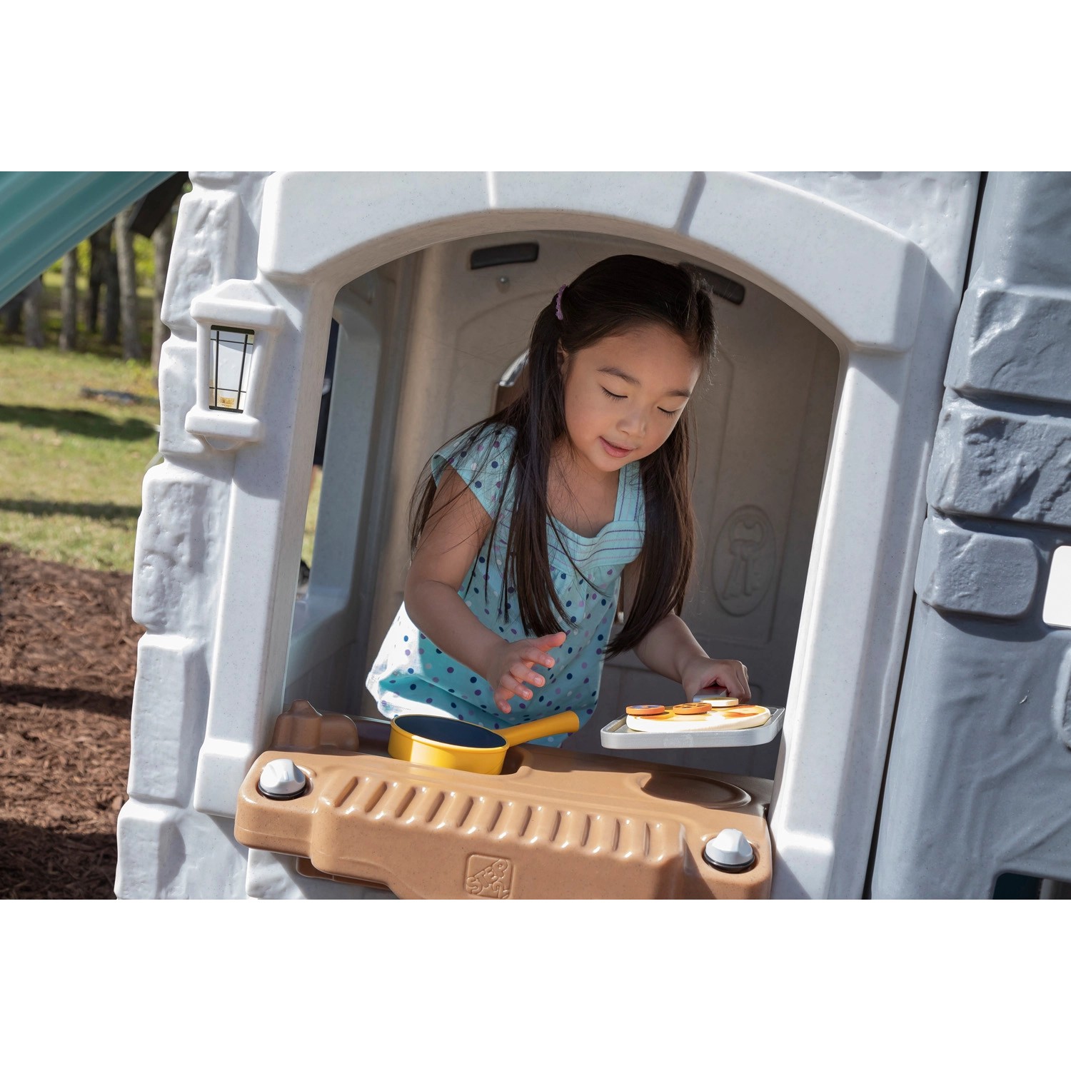 Mädchen spielt im Step2 Adventures Spielhaus mit Küche und Rutsche.