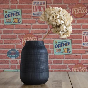 Tadessi Vliestapete Stein Eliano, braun-rote Steinoptik, mit Vase und Blume vor der Steinwand.