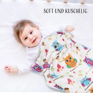 Baby mit Bestlivings Kuscheldecke Cashmere Dots Kids Eule im Kinderbett.