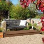 Terrassendiele Nadelholz braun, 6 Rillen, auf Terrasse mit Bank und Bepflanzung.